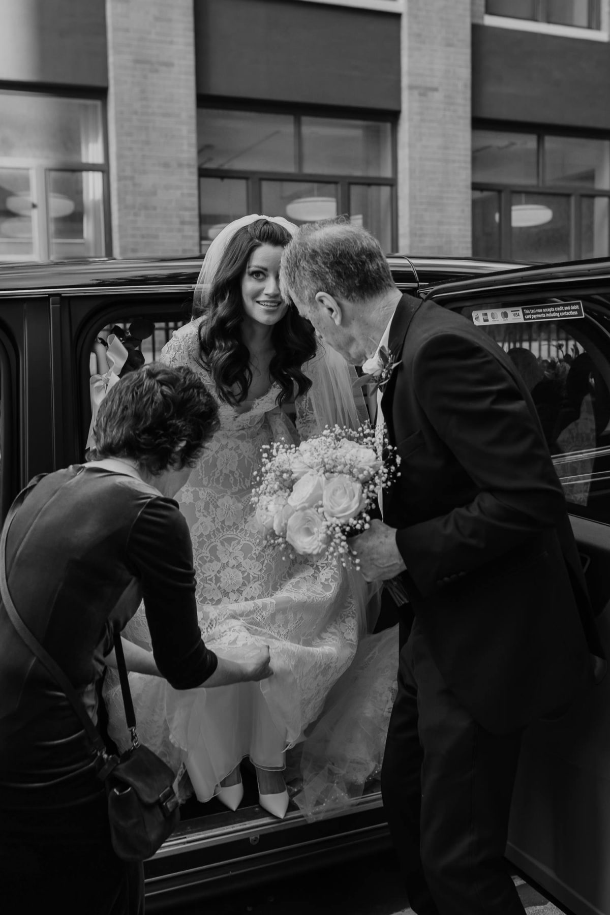 bride is being helped getting off the car for fitzrovia chapel wedding