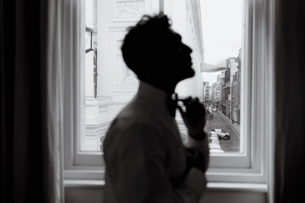groom is getting ready against window at No Mad London hotel